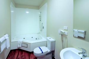 a bathroom with a toilet and a sink and a tub at 540 on Great South Motel in Auckland