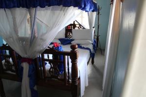 a bedroom with a canopy bed with white curtains at Princess Salme Inn in Zanzibar City