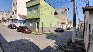 a street with cars parked in front of a building at Casa para 9P com escada sem garagem in Aparecida