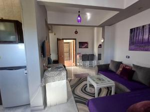 un salon avec un canapé violet et un réfrigérateur dans l'établissement Holiday Apartment in Sunshine - Naama Bay, à Charm el-Cheikh