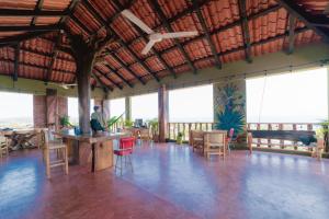 a large room with tables and chairs and windows at Madre Tierra Hostal in Puerto Escondido