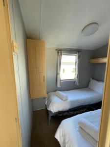 ein kleines Zimmer mit zwei Betten und einem Fenster in der Unterkunft Newquay Bay Holiday Resort Caravan 142 in Newquay Bay Resort + 24 Fotos