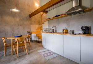 a kitchen with white cabinets and a table and chairs at Casa Cândida e a Casa do Lado in Abadim