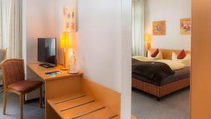 a bedroom with a bed and a desk with a television at Hotel Skada City Cölln in Cologne