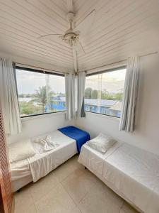 twee bedden in een kamer met een groot raam bij Pousada Novo Horizonte in Búzios