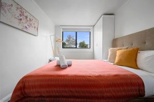 a bedroom with a large bed with a red blanket at Burnie City Apartments in Burnie