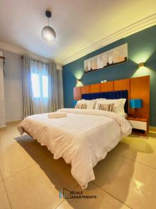 a bedroom with a large white bed with a blue wall at Scale Apartments in Douala
