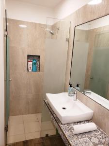 a bathroom with a sink and a shower with a mirror at Casa Aura in Isla Mujeres