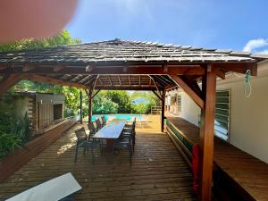 a wooden deck with a table and chairs under a pergola at Kazajany in Terre-de-Haut