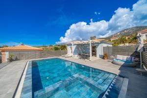 a swimming pool with a patio and a house at Villa Dandelion in Kefallonia