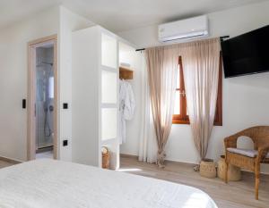 a bedroom with a white bed and a television at Olea White in Skiathos
