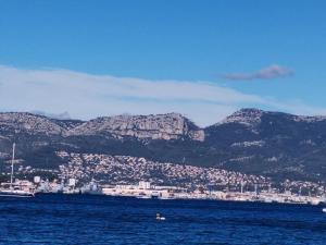 una persona nadando en el agua con montañas en el fondo en Taîaut, en La Seyne-sur-Mer