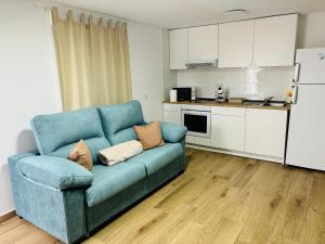a blue couch in a living room with a kitchen at Libertad B in Santiponce