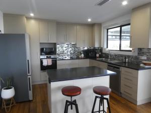 a kitchen with white cabinets and black counter tops at Moonta Bay Stylish large home 3 min walk from beach and jetty in Port Moonta