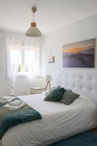 a white bedroom with a large white bed with pillows at Beachfront apartment T2 Costa Nova Surf Aveiro in Gafanha da Encarnação