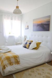a white bedroom with a large white bed with pillows at Beachfront apartment T2 Costa Nova Surf Aveiro in Gafanha da Encarnação
