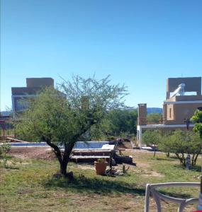 un árbol en un campo con edificios en el fondo en Cuatro Elementos Housing, en Villa Santa Cruz del Lago