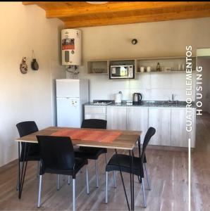 Una cocina con una mesa de madera y sillas negras. en Cuatro Elementos Housing, en Villa Santa Cruz del Lago