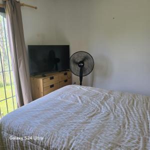 a bedroom with a bed and a flat screen tv at Cabaña MISUEÑO in Punta Del Diablo +14 photos