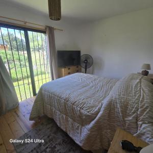 a bedroom with a bed and a large window at Cabaña MISUEÑO in Punta Del Diablo