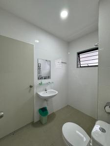 a white bathroom with a toilet and a sink at Sungai Long Guesthouse in Kajang