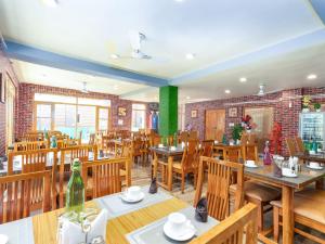 a restaurant with wooden tables and chairs and a green wall at Hotel River View Resort in Pahalgām