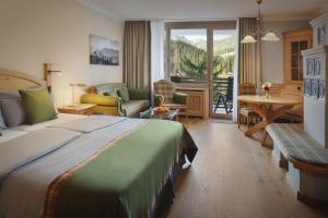 a hotel room with a bed and a living room at Arabella Alpenhotel am Spitzingsee, a Tribute Portfolio Hotel in Spitzingsee