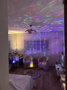 a room with a ceiling with purple and pink lights at Appartement Relaxe in Carquefou +3 photos