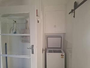a white kitchen with a refrigerator and a door at Windy Garden in Marahau +33 photos