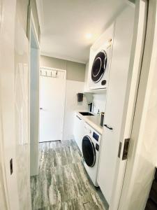 a small white kitchen with a washer and dryer at The Sea Urchin in Tuross Heads
