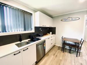a kitchen with a sink and a table with a chair at The Sea Urchin in Tuross Heads