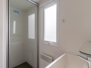 a white bathroom with a window and a sink at Mobil-home 6 pers, camping 3 étoiles à 5km de l'océan, piscine chauffée, activités familiales - FR-1-50-144 in Saint-Julien-en-Born