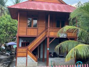 una casa in legno con balcone sopra di MAXWELL Pondok Wisata a Likupang