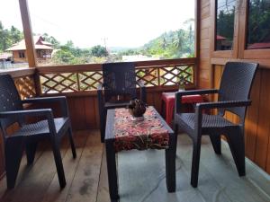 un portico con due sedie e un tavolo con di MAXWELL Pondok Wisata a Likupang