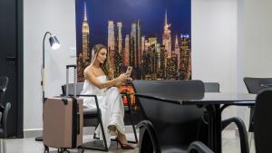 a woman sitting in a chair looking at her cell phone at TNY Apart-Hotel in Barretos