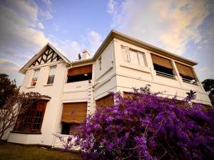 a white house with purple flowers in front of it at Sunny Brae Manor in Great Brak River