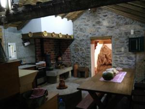 a kitchen with a table and a stone wall at Moinho da Cruz in Ponte de Lima