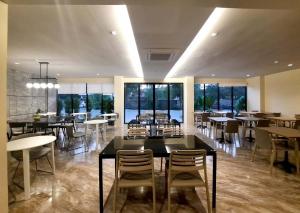 a dining room with tables and chairs and windows at The 9 Residence Hotel in Bangkok