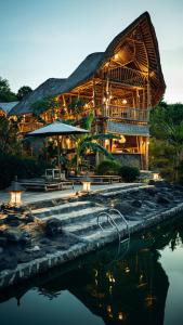 ein großes Holzgebäude mit einem Pool aus Wasser in der Unterkunft Penida Bambu Green Suites in Nusa Penida