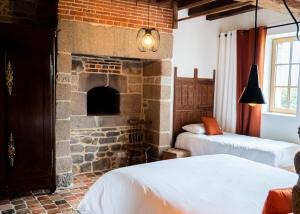 a room with two beds and a stone fireplace at Le Fournil du Bertry in La Bouexière