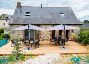 a wooden deck with tables and chairs and umbrellas at Le Fournil du Bertry in La Bouexière