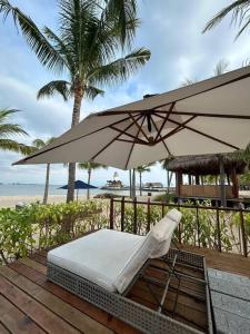 a chair and an umbrella on a deck with the beach at Casa de lujo con alberca y playa privada in Cruz de Huanacaxtle