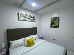 a bedroom with a white bed with a yellow pillow at HST - 3BED Duplex Chevron - Lekki in Ikuata