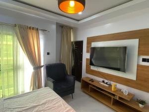 a bedroom with a bed and a tv and a chair at HST - 3BED Duplex Chevron - Lekki in Ikuata