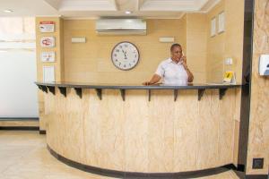 a man standing behind a counter with a clock on the wall at Sleep Inn Hotel - City Centre in Dar es Salaam +85 photos