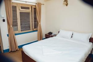 a bedroom with a large white bed and a window at Buddha Home Nepal in Thapathali