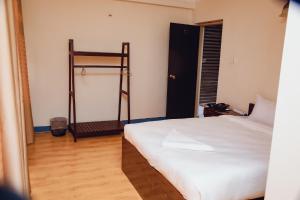 a bedroom with a white bed and a wooden floor at Buddha Home Nepal in Thapathali +1 photo