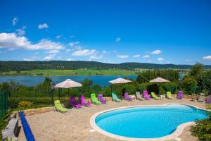 a pool with chairs and a view of a lake at Hôtel Beau Site in Malbuisson