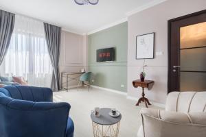 Una sala de estar con sillas azules y una mesa. en Moonlight Central Apartments, en Oradea