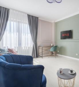 Una sala de estar con un sofá azul y una mesa. en Moonlight Central Apartments, en Oradea